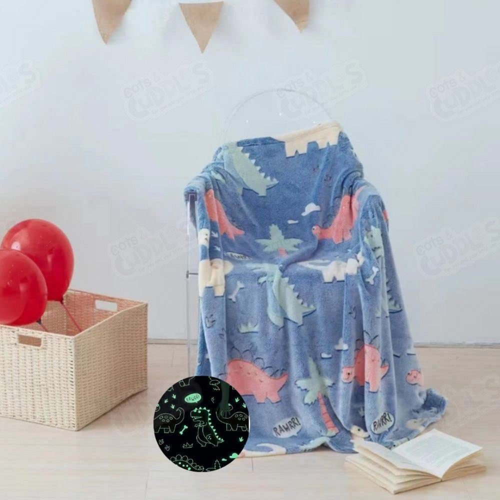 Blue dinosaur-themed plush baby blanket with glow-in-the-dark features draped over clear chair
