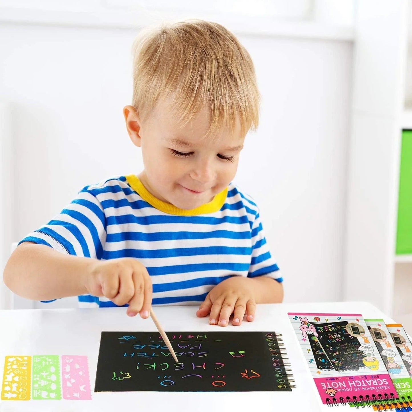 Child playing with colorful NIYO TOYS return gift scratch note art set at a white table