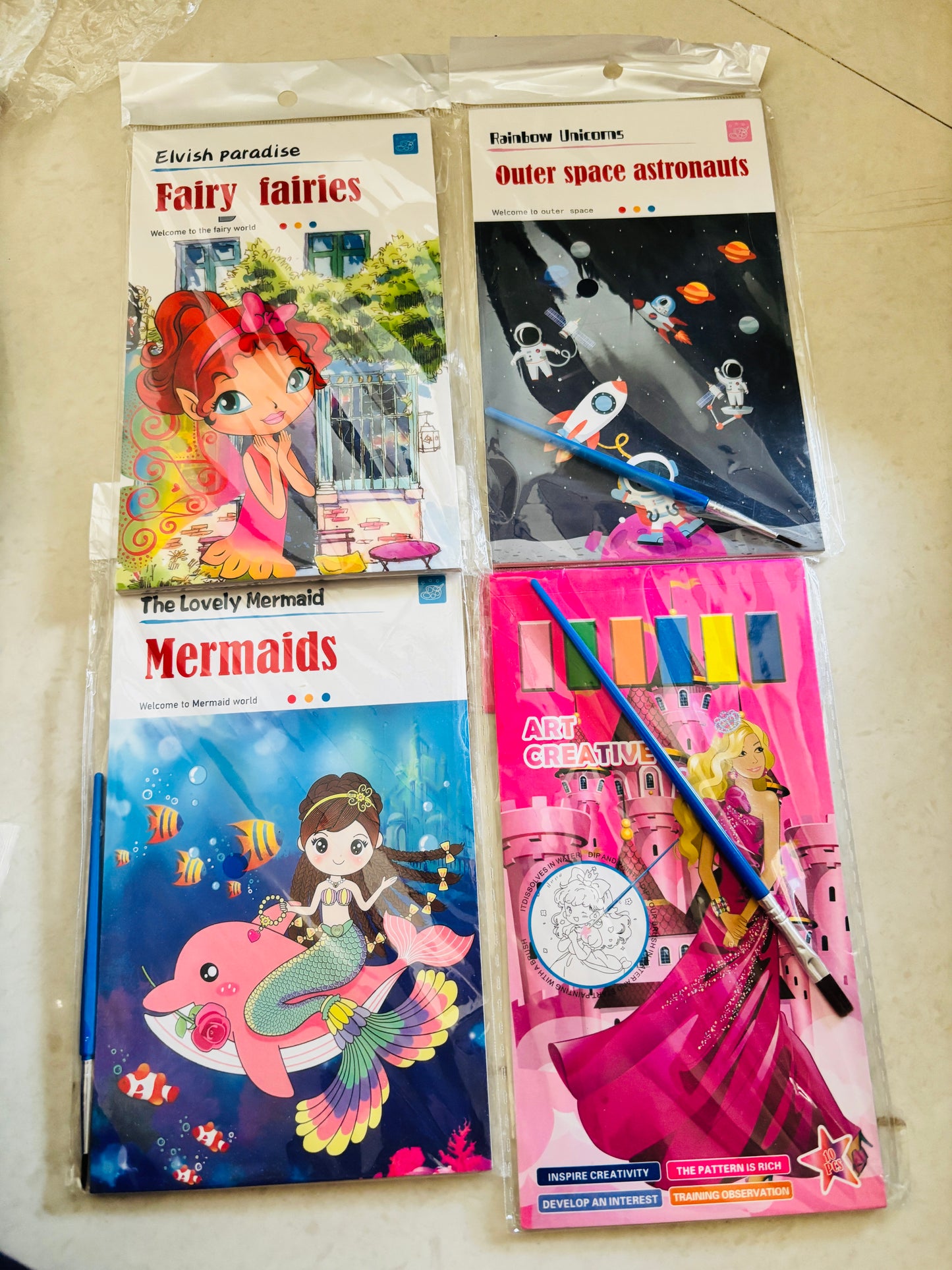 Four colorful magic water painting books for kids featuring fairies, astronauts, mermaids, and creative art activities
