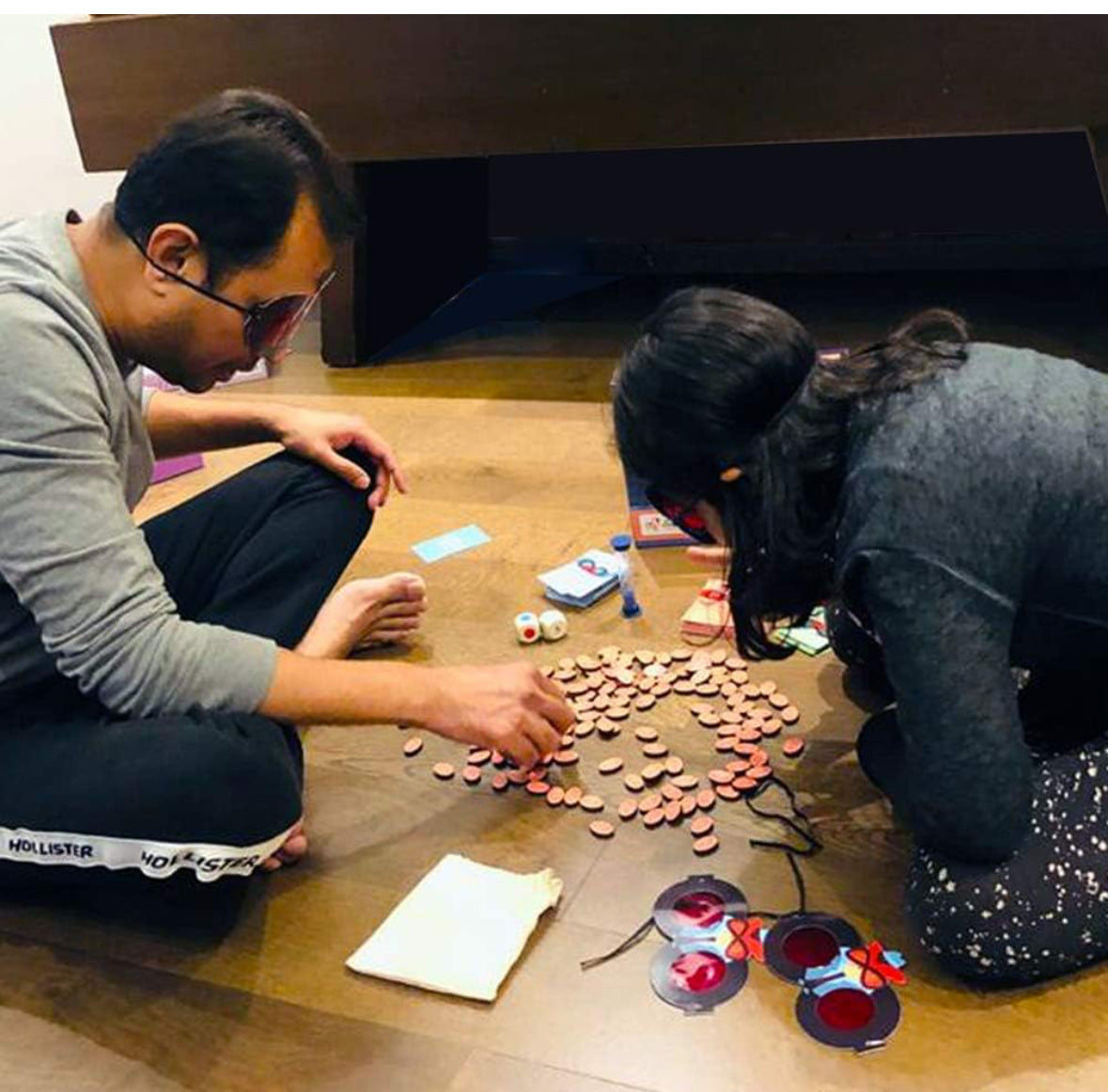 Family playing cross word game free on a wooden floor, using letter tiles and enjoying fun together