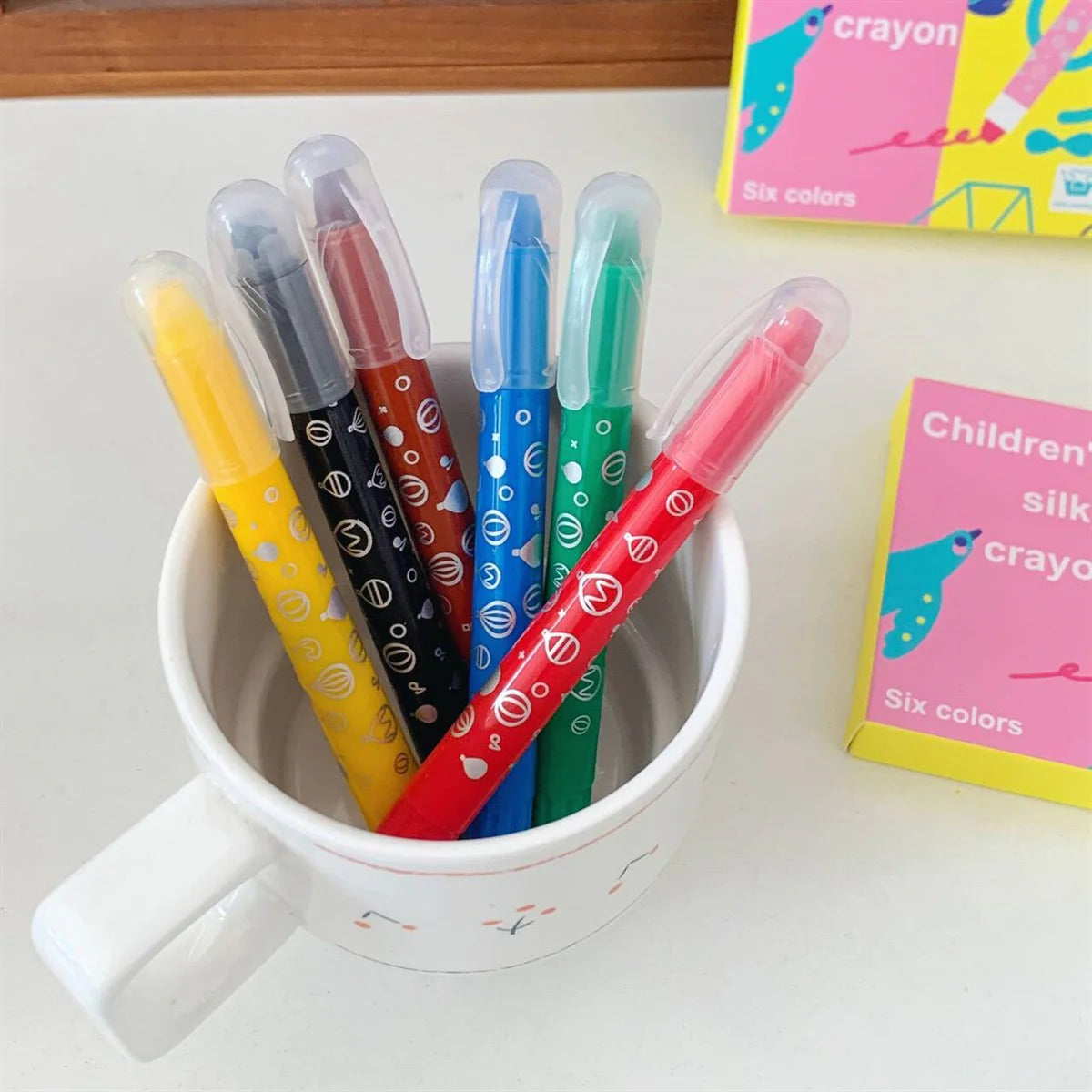 Set of six colorful silky crayons in a cup, designed for children age 3+, ideal for creative art projects