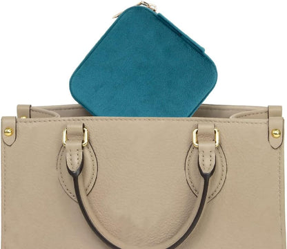 Teal jewelry case for travel fitting perfectly in a stylish beige handbag