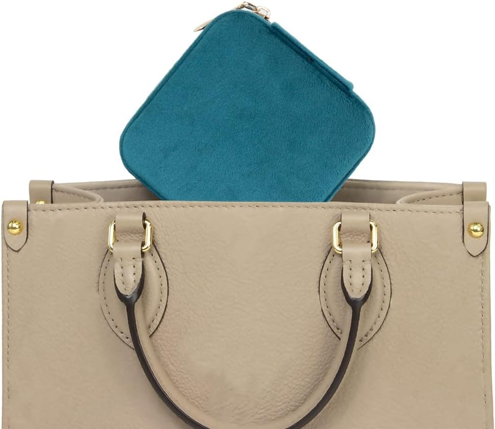 Teal jewelry case for travel placed inside a stylish beige handbag for easy organization