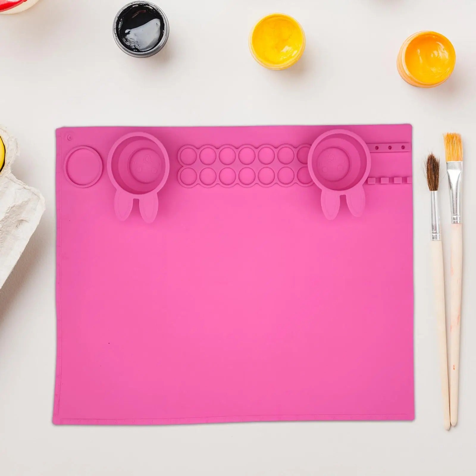 Bright pink silicone art mat for kids with paint cups and tools for creative activities