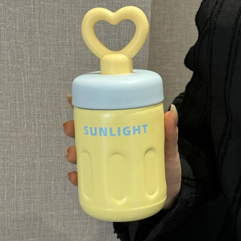 Yellow heart-shaped handle tumbler with 'SUNLIGHT' text, perfect for kids age 3+, ideal for on-the-go hydration
